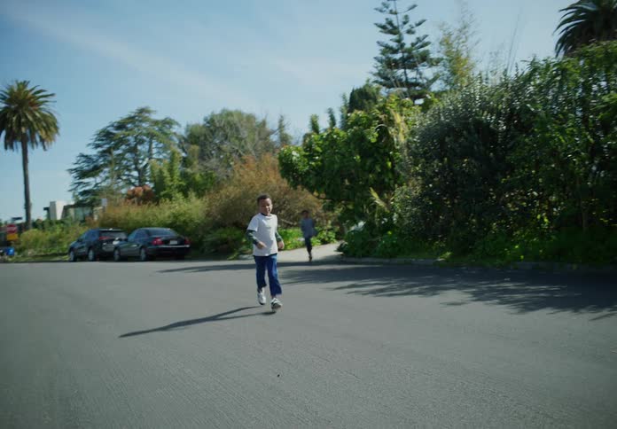 Brothers run from driveway onto street and stand waving goodbye