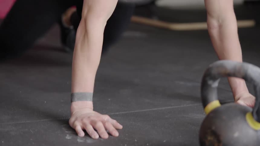 A woman does a quick push up on the gym floor before running off