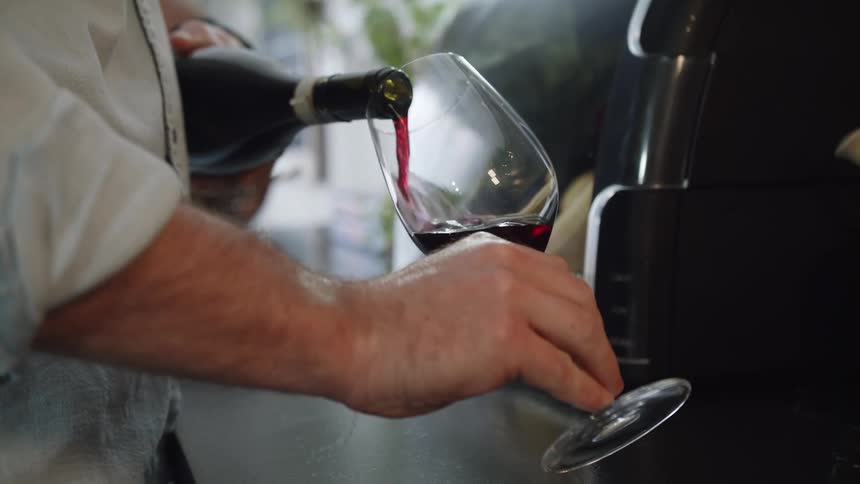 Man pouring red wine into wine glass