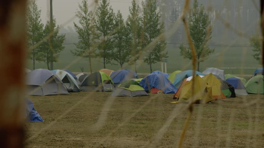 Group of colorful mountain tents set up on a field in the countryside next to a road at morning
