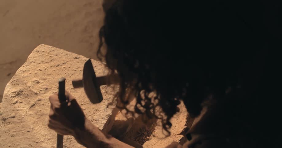 A man is carving stone with a hammer and chisel