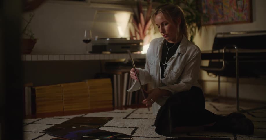 A woman sitting on her floor looking through record albums