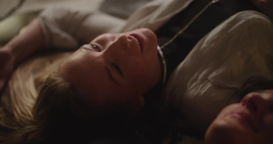 Two women lay on the floor next to each other while conversing