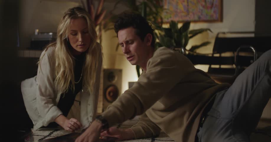 A man and woman go through vinyl albums while sitting on the floor