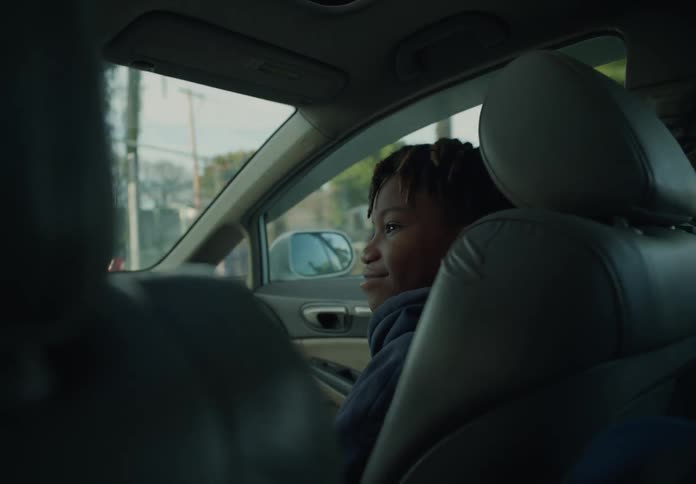 A young boy sitting in the front seat of a car as it is driven down the road in a tropical area