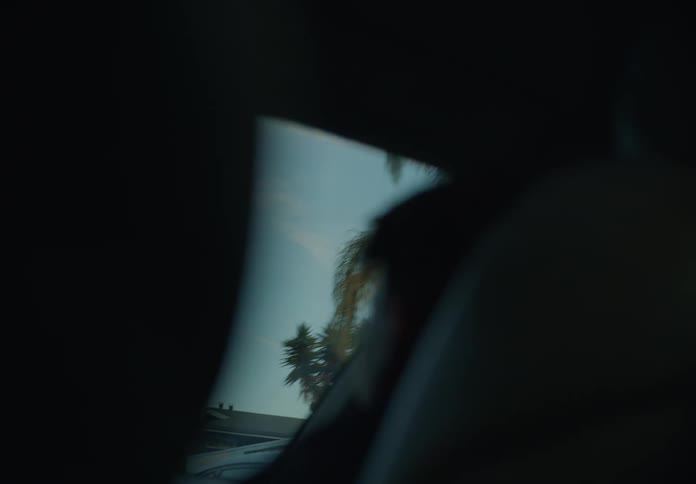 A sliver of sky and trees are visible through the windshield of a car