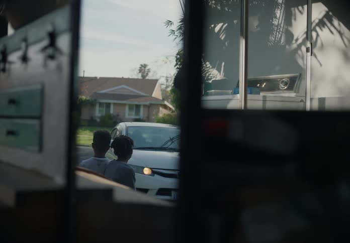 Two young boys hug their mother before she drives off in a car