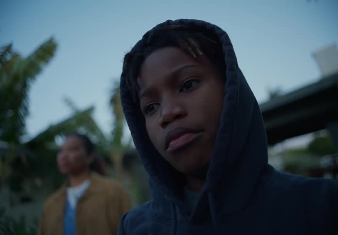 Mother stands in the front yard with her sons wearing hoodies on a cold morning