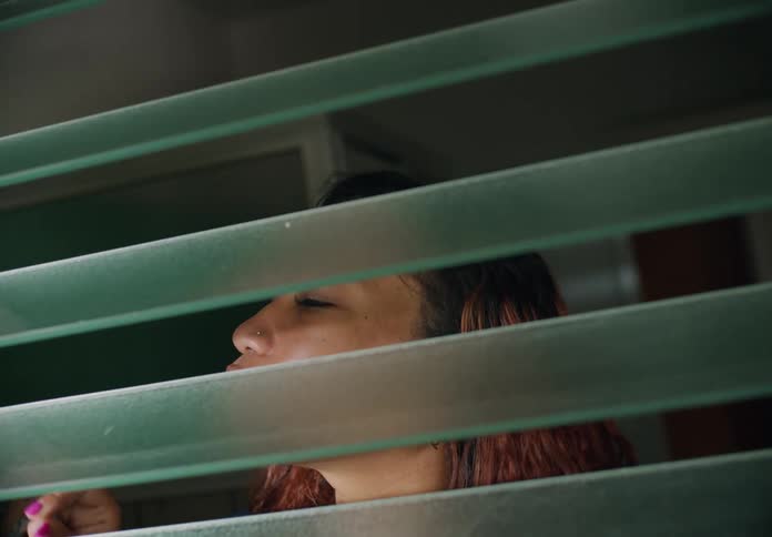 Woman with earrings and red curly hair closes blinds