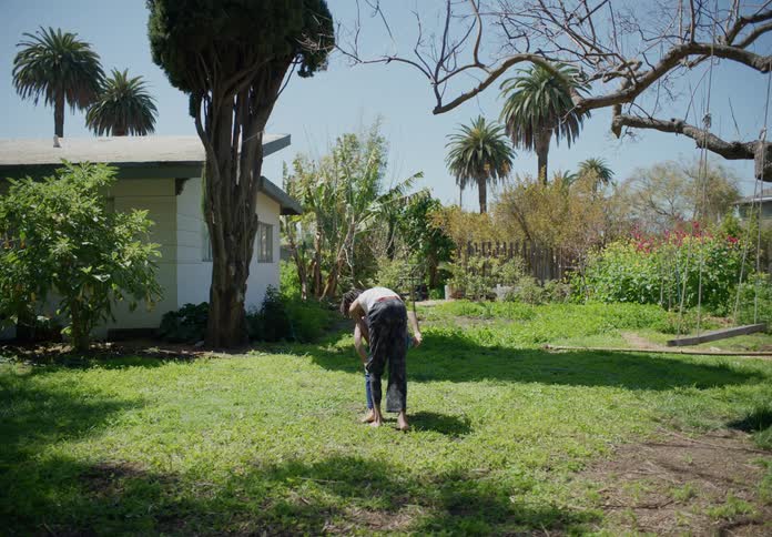 Two boys wrestle and play in a yard near a swing and trees
