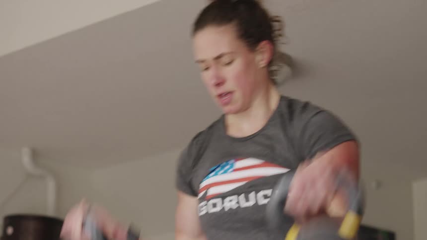 Woman lifts weights while exercising in home gym