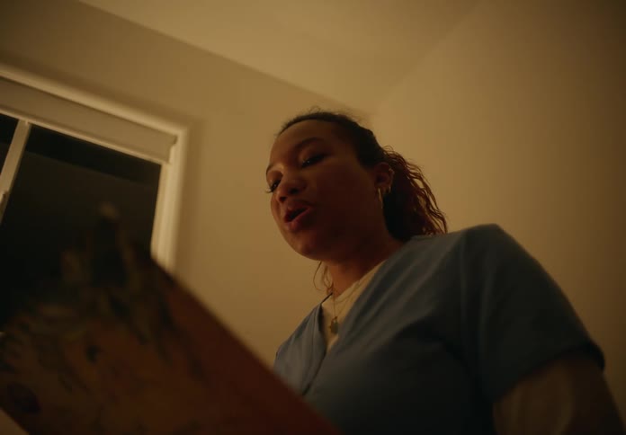 A woman reading out of a book while she looks around her at other people in the room