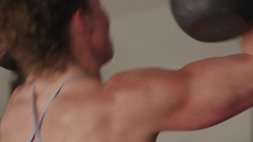Woman lifts hand weights in home gym