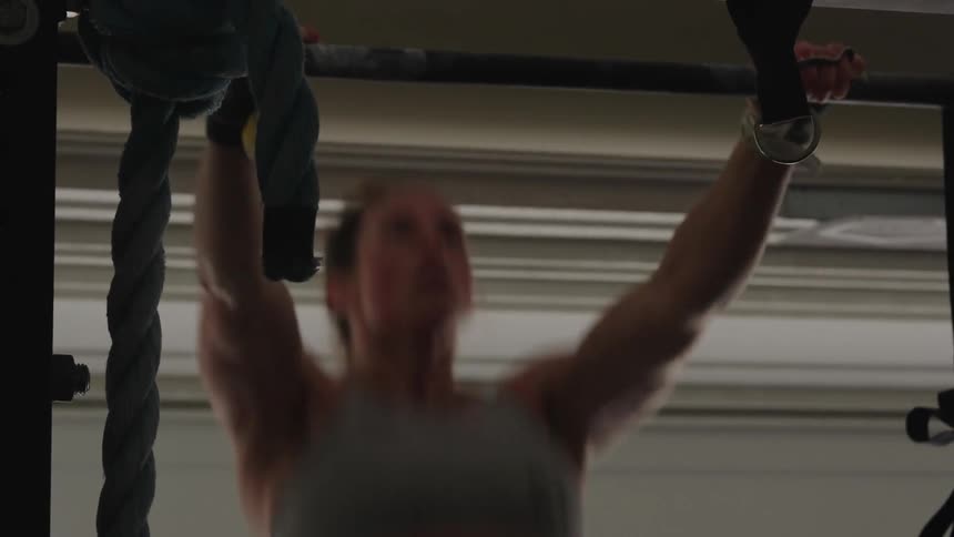 A woman lifting herself to do pull ups on a bar