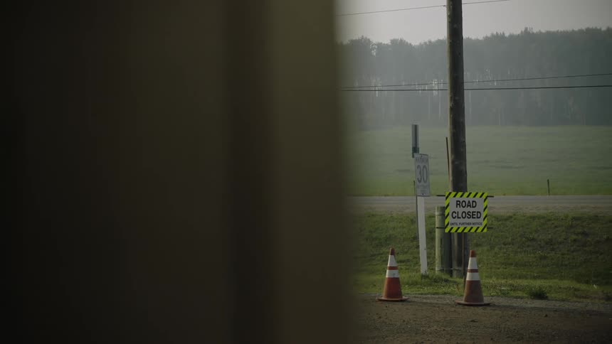 A view of a sign on a pole next to a road