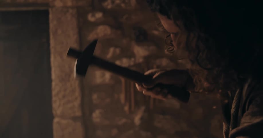 A man uses a hammer and chisel to shape a block of stone