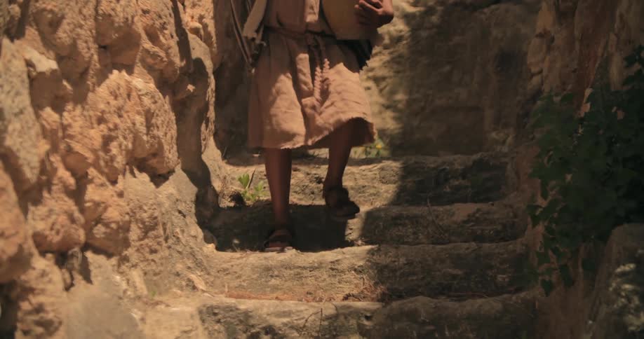 Young boy from traditional biblical times runs down the stairs carrying a vase