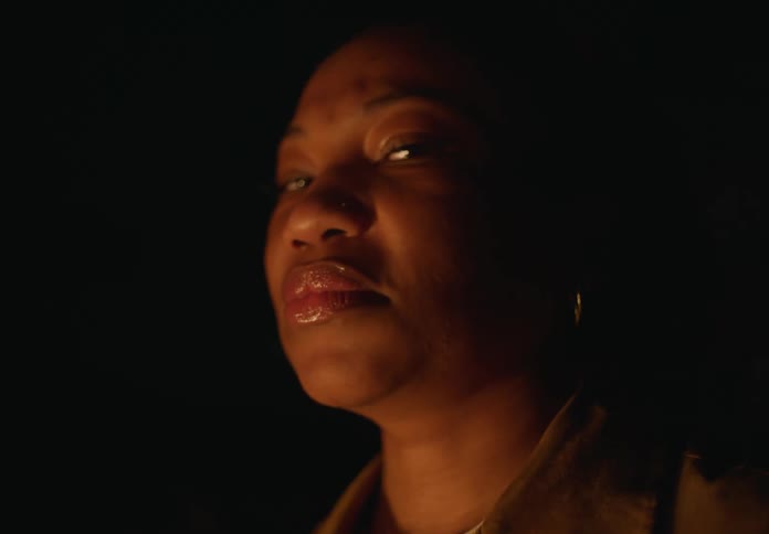 Woman standing inside a dark room during a blackout comes into focus looking at the camera