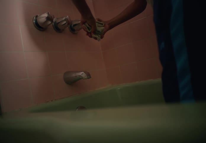 A person shuts the water off in the tub