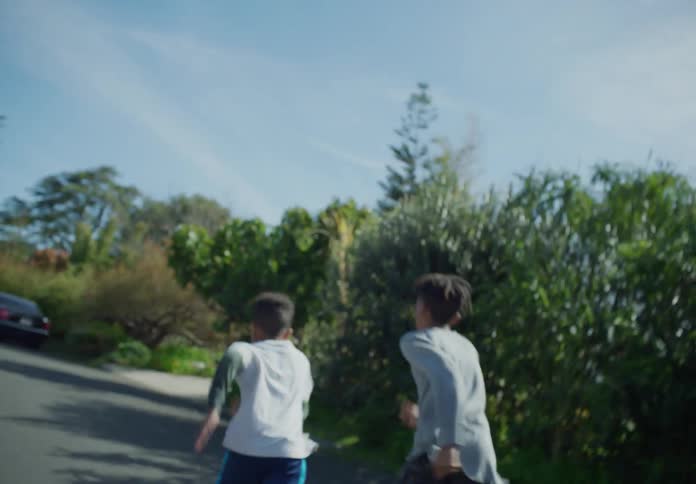 Boys with dreadlocks and sweaters shirt and pants run a race in the street