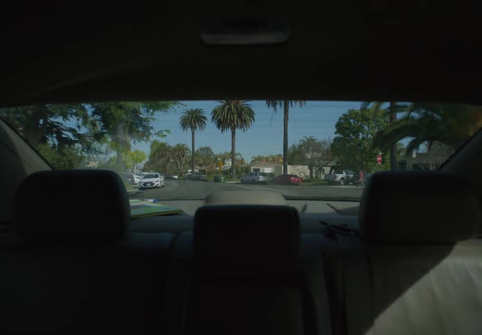 The streets of a neighborhood seen from the back window of a moving vehicle