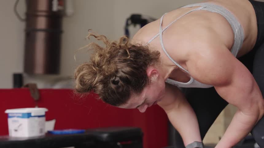 Woman tries to catch her breath before she continues exercising in home gym