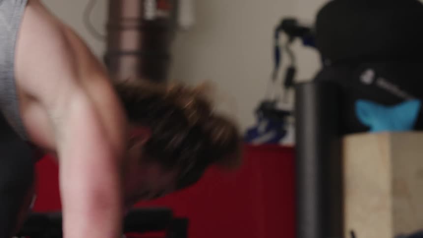 A woman is doing a combination of jumps and pushups in a gym