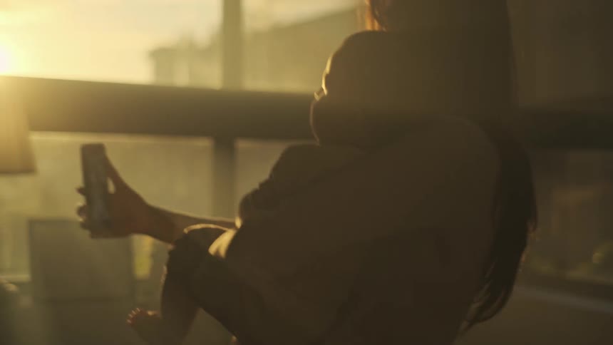Silhouette of a mother holding her son in front of a window takes a selfie