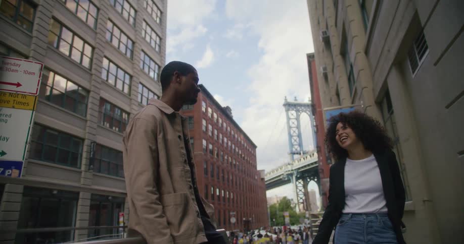 A man and woman chat while standing at a bus stop downtown
