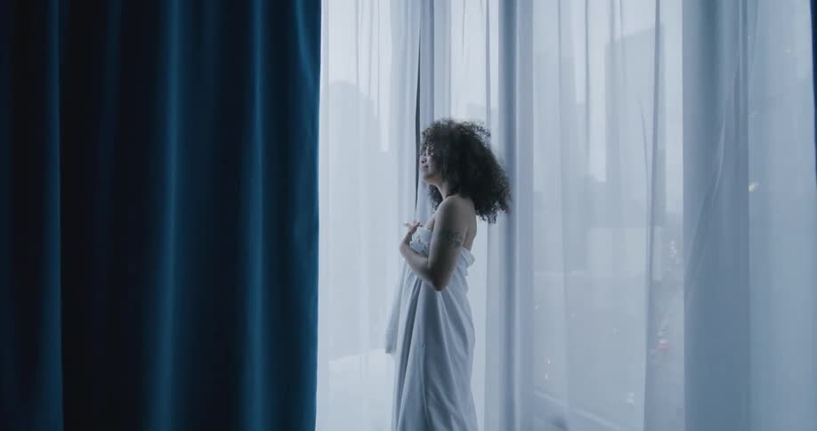 A woman is standing by a window in a building