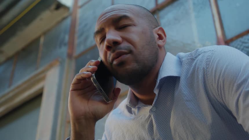 A man is standing outside near a building talking on his cell phone