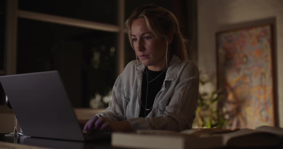A woman is sitting at a desk typing on her laptop
