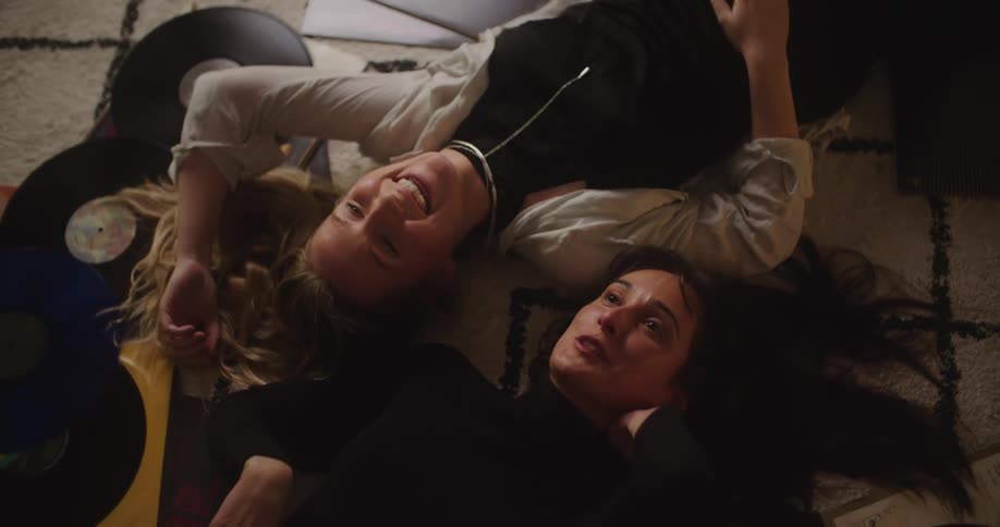 Two women lying on the floor talking laughing and listening to records