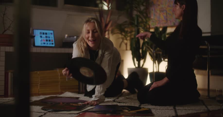 A couple of young friends sitting on the floor of the living room playing vinyl records