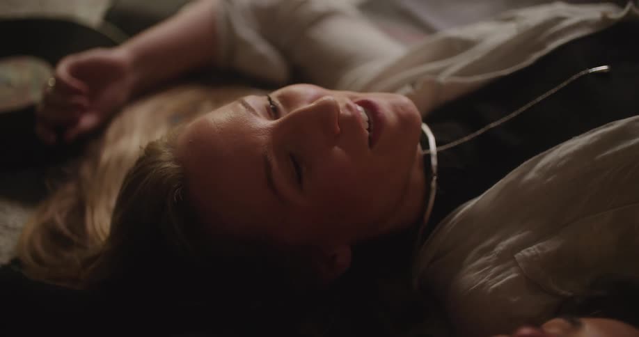 Two young friends have a conversation while laying on the living room floor next to each other