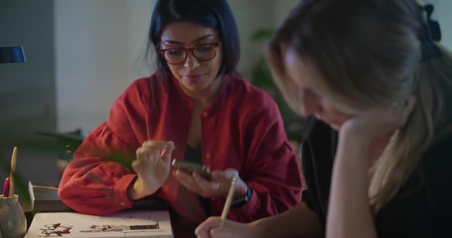 Two female coworkers checking information on a smartphone while working at the office