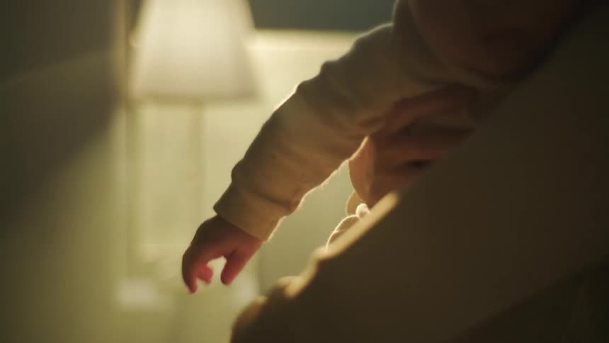 A close up of a mother holding her baby in her arms and readjusting