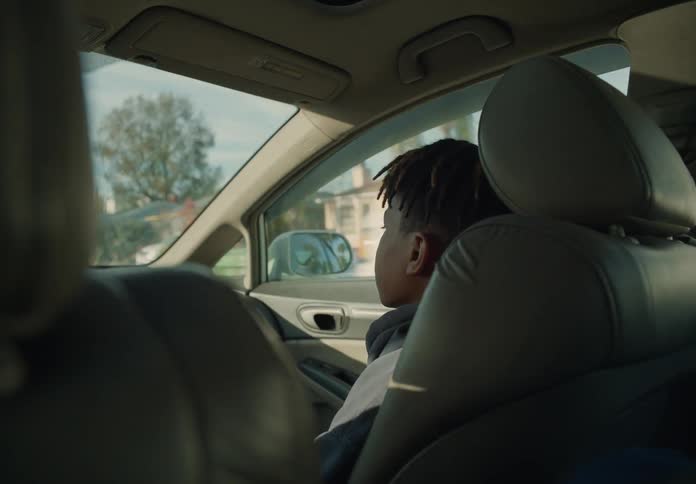 Teen boy in passenger seat of car during the day probably on the way to school