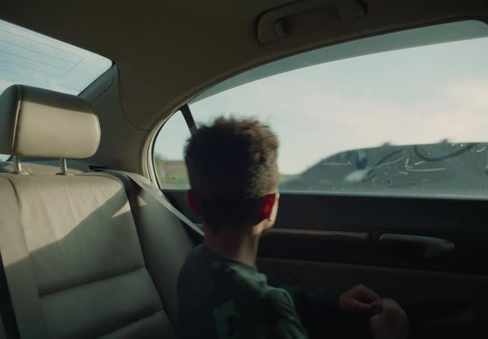 Young boy sitting in backseat of car looking out the window
