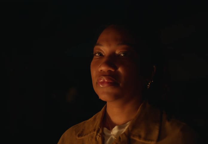 Woman at nighttime looking up at the sky and then tilting head downward and looking into the camera