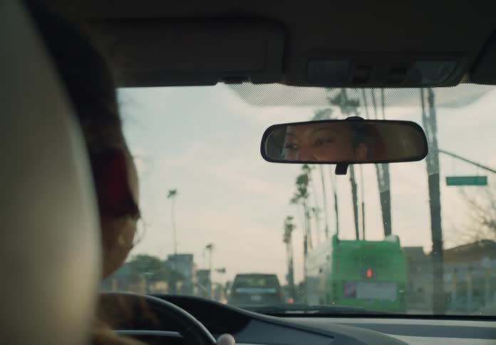 A woman is looking in her rear view mirror while driving on a busy city street
