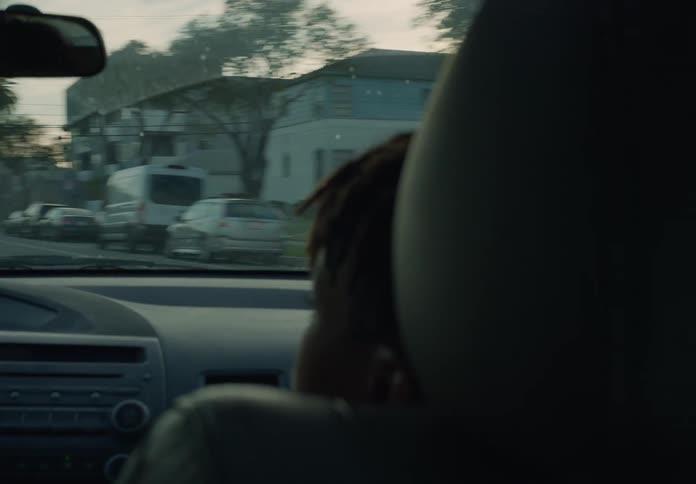 Teen boy riding in passengers seat of car at sundown probably with his mom driving
