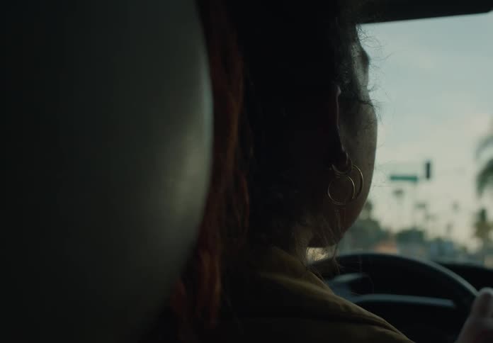 A woman drives a vehicle along a street in the evening