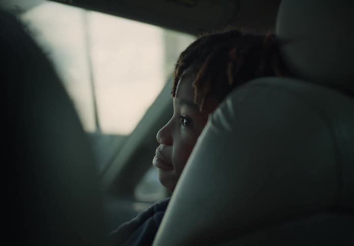 Youth watches the driver as he rides in front passenger seat of a moving vehicle