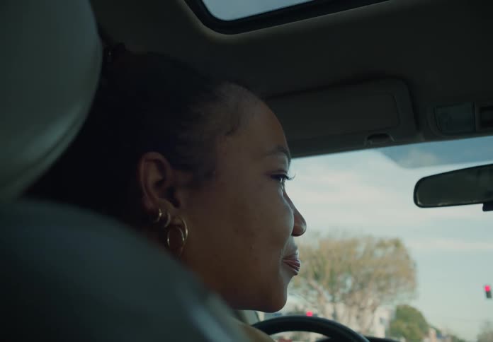 A woman is sitting behind the steering wheel of an automobile as she drives the car
