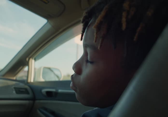 A close up of a boy sleeping while riding in a moving car