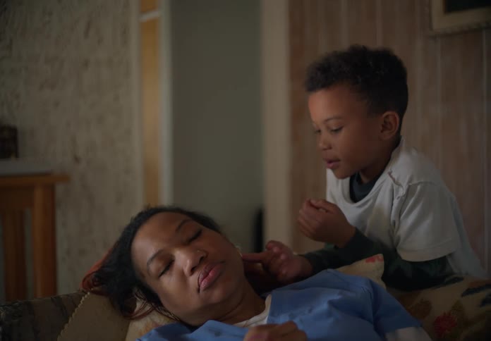 A boy checks on his sleeping mother