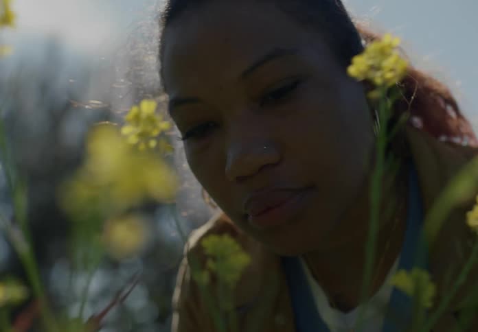 A close up of a womans face in front of flowers as she looks at them