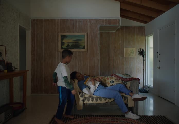 Young boy comes into living room finds mom asleep on the couch covers her with a sweater