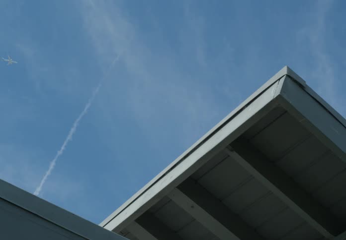 The plane flies over the roof